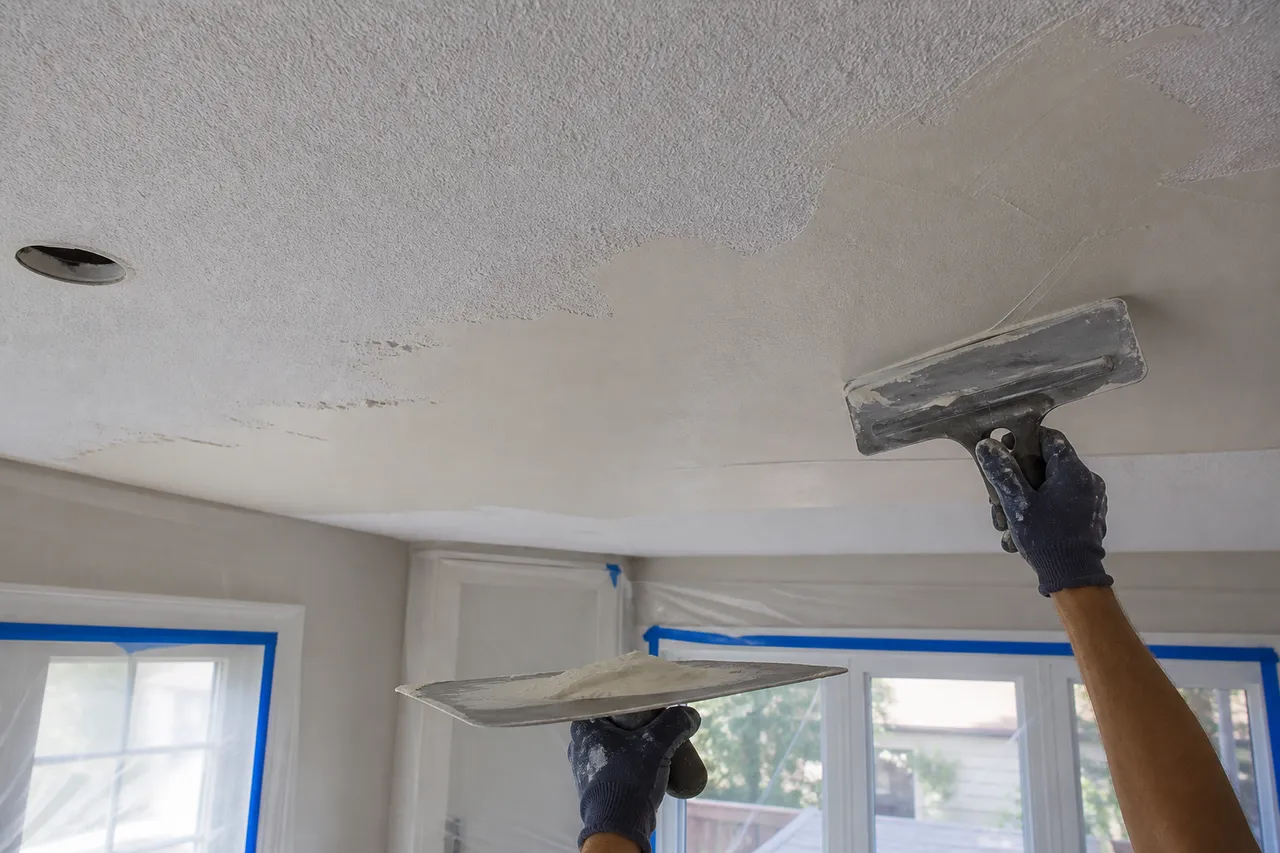 Skim coating prepared painted popcorn ceiling in a protected room