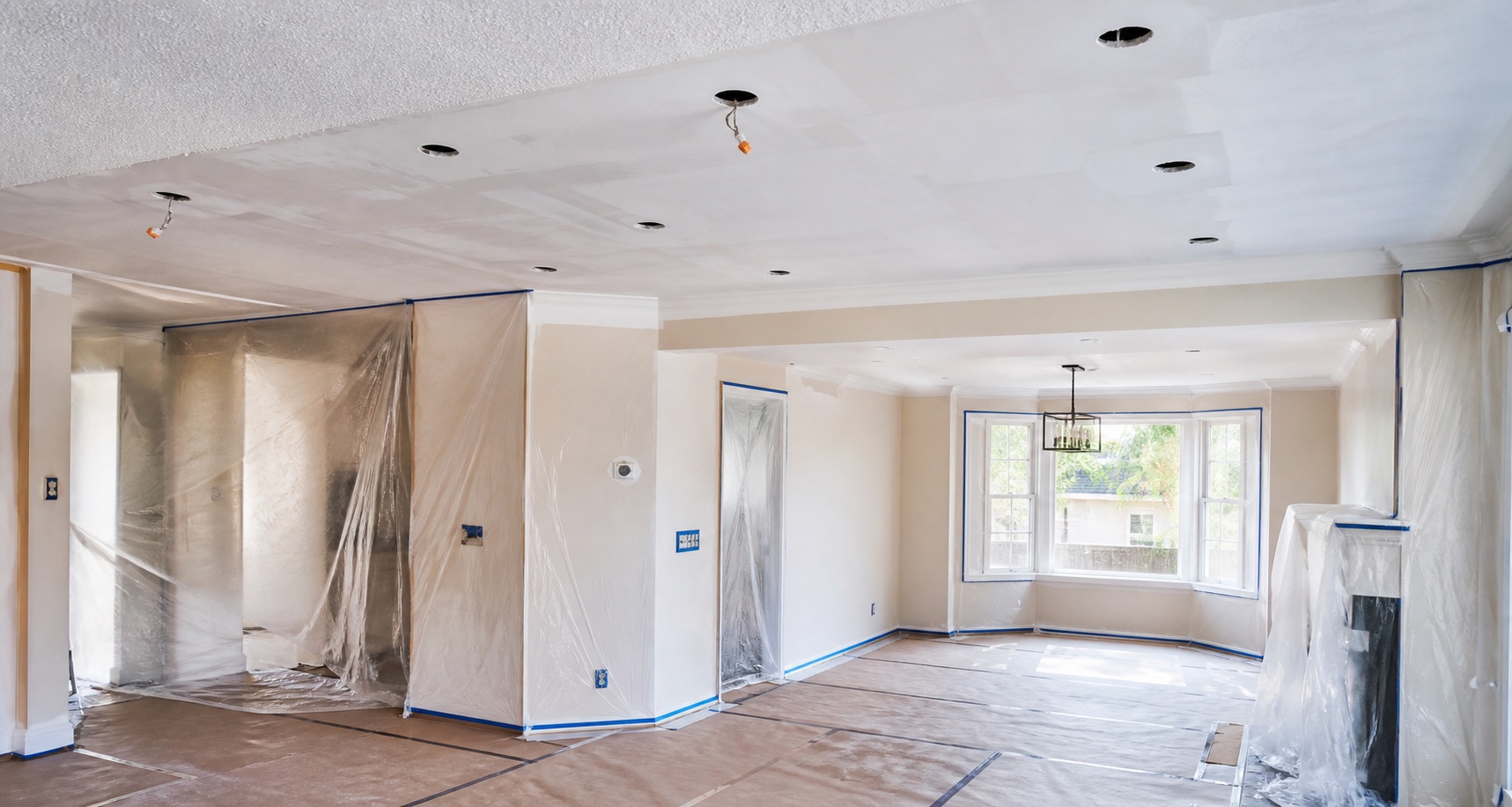 Protected renovation room with popcorn ceiling preparation and recessed light openings planned before finishing